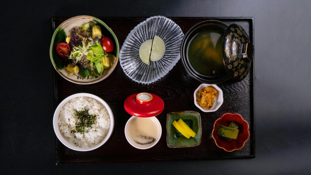 pexels-photo-20802555-20802555 Top view of a traditional Japanese meal with rice, soup, salad, and side dishes on a tray.