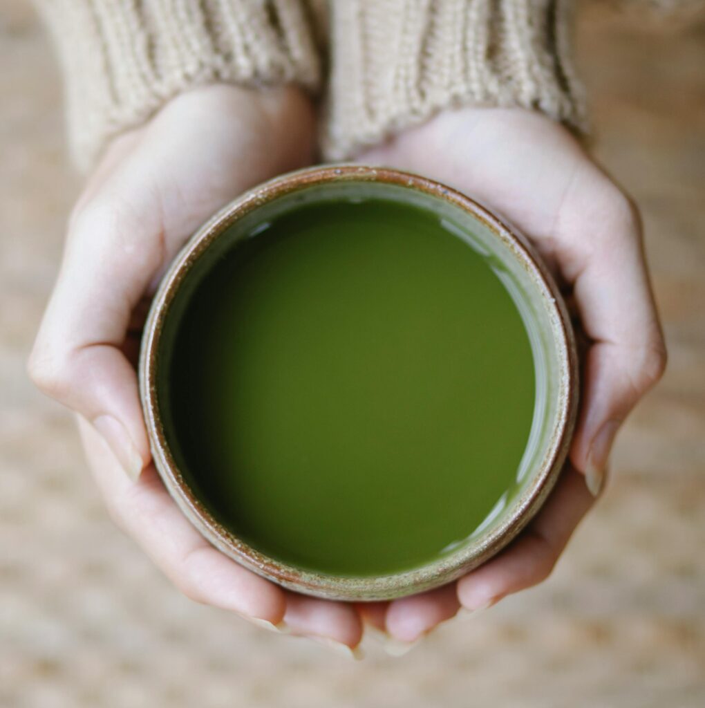 pexels-photo-5946652-5946652 Top view of crop anonymous female showing bowl full of green tea of matcha in hands on blurred background